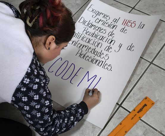 Eine Mitarbeiterin von CODEMUH malt ein Plakat für eine Demonstration.