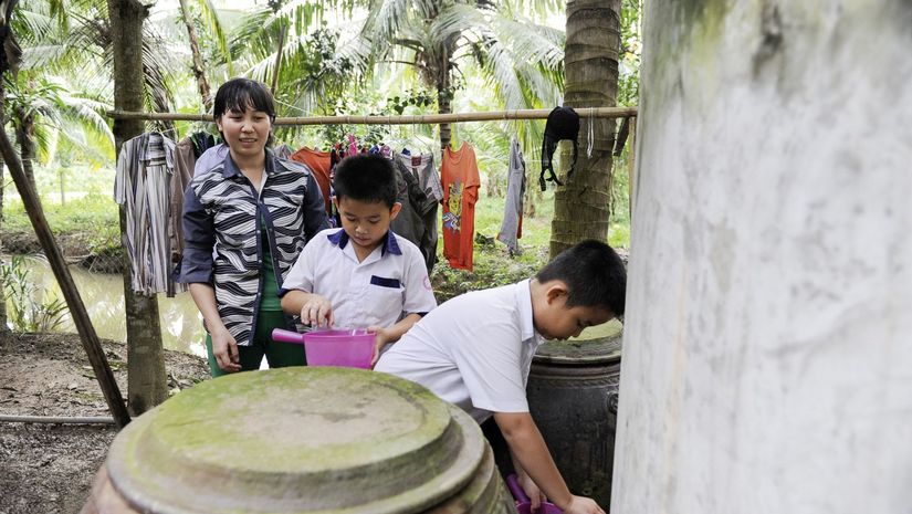 Kam Kim Phuong und ihre Kinder beim wasserholen am Wassertank