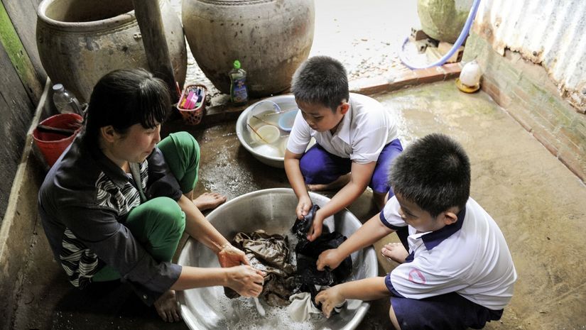 Kam Kim Phuong und die Kinder waschen die Wäsche in einer großen Schüssel