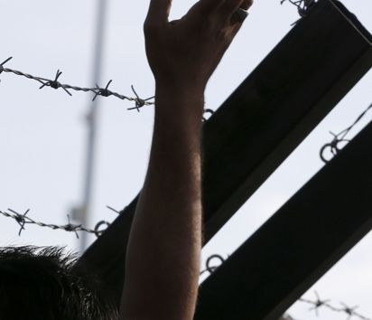 Nach der von ungarischer Seite beschlossene Abriegelung des Grenzuebergangs Horgos-Roeszke lagern die zumeist aus Syrien, Irak und Afghanistan kommenden Fluechtlinge im Niemandsland. Viele der Fluechtlinge demonstrieren gegen Schliessung der Grenze. Foto: Fluechtlinge lassen sich in ihrem Protest vom Stacheldrahtverhau der urgarischen Grenzanlage nicht abhalten.