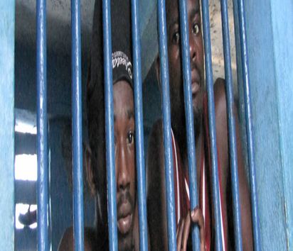 Gefangene hinter Fenstergitter einer heruntergekommenen Zelle, Vorfuehrzellen (Garde à vue) der Polizeistation, Kommissariat von Jérémie, Haiti, Grande Anse, Jeremie | detainees behind bars of a window in run-down predetention cell (garde à vue) at police station, commissariat of Jérémie, Haiti, Grande Anse, Jeremie