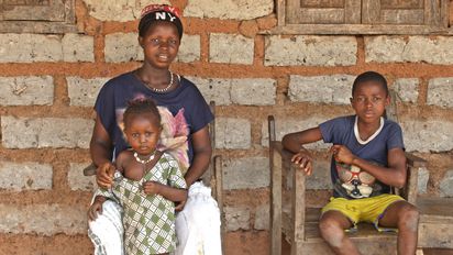 Hawa Conteh sitzt in Sierra Leone mit ihrer Familie vor ihrem Haus.