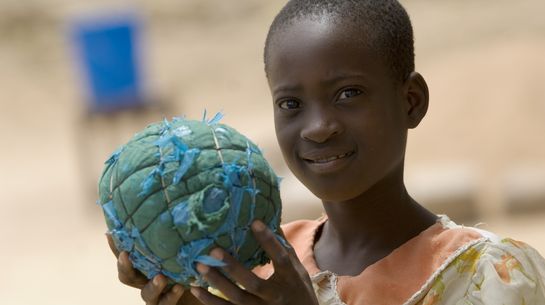 Ein Junge hält einen Fußball der an den Planeten Erde erinnert.