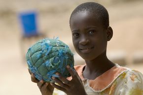 Ein Junge hält einen Fußball der an den Planeten Erde erinnert.