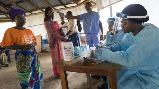 Vor dem Elwa Hospital in Monrovia kontrolliert ein Krankenhaus-Mitarbeiter die Temperatur eines Patienten.