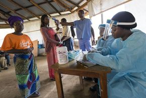 Vor dem Elwa Hospital in Monrovia kontrolliert ein Krankenhaus-Mitarbeiter die Temperatur eines Patienten.