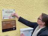 Brigitte Molter bringt das neue Siegel auf dem Faire Gemeinde-Schild an.