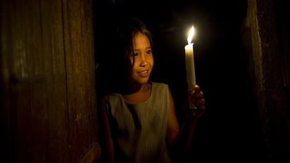 Ein Mädchen vorm Abendessen im Kerzenschein in der Region Srangani Province, Philippinen