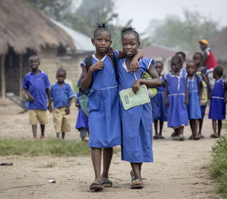 Gemeinsam mit ihrer Freundin Fatmata Sheriff (1. Person v. links, 9 Jahre) geht Mbalu Tarawallie (8 Jahre) allmorgendlich in die Dorfschule. Projektpartner: SIGA (Siera Grassroots Agency)