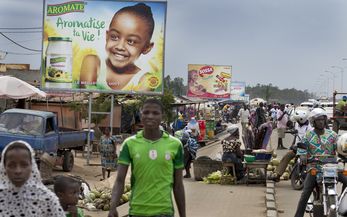 Ausland, Afrika, Westafrika, Togo, Ressourcen, Ernährung, Ernährungssicherheit, Nahrung, Lebensmittel, Nahrungsmittel, Grundnahrungsmittel, Landwirtschaft, Kleinbauern, Roherzeugnis, Verbraucher, Konsument, Ausland, Europa, Importprodukt, Werbung, Werbeplakat, Marktbesucher, Marktstand, Mann, Straße, Markt, Plakat, Verkehr