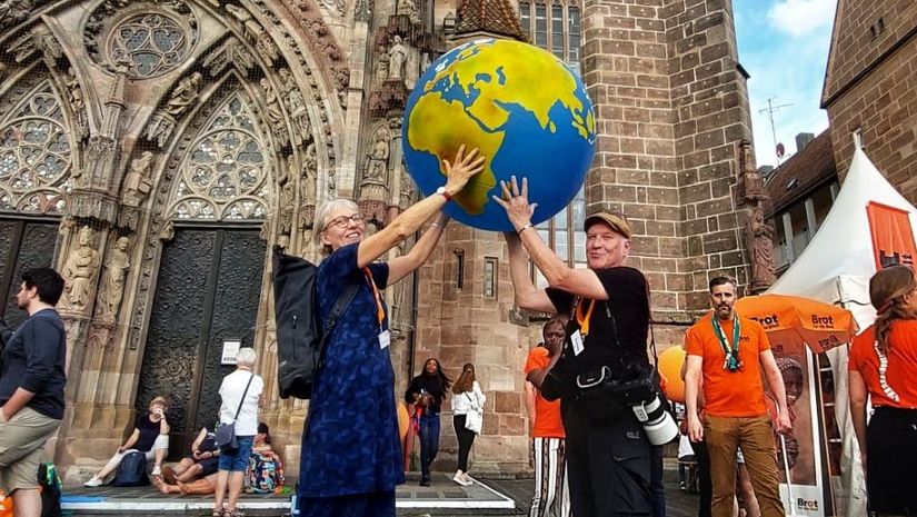 Mitarbeitende und Fotograf halten eine Weltkugel in die höhe