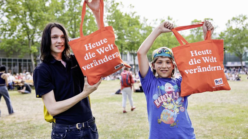 Junge Kirchentagsbesucher mit „Brot für die Welt“ Beutel vor der Open Air – Bühne im zentralen Messepark, beim Kirchentag 2023 in Nürnberg.