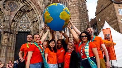 Stipendiaten von BFDW mit Weltkugel beim Konzert der A capella Band "Füenf"  auf dem Hauptmarkt in Nürnberg beim Kirchentag 2023 .