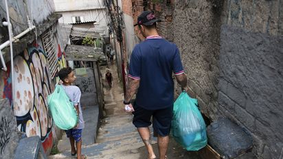 Vinnicius Fragoso (26) Koordinator des Projektes Futebol de Rua, begleitet Thaylor Pietro Souza Santos (12) nach Hause, Sapopemba, Sao Paulo, Brasilien