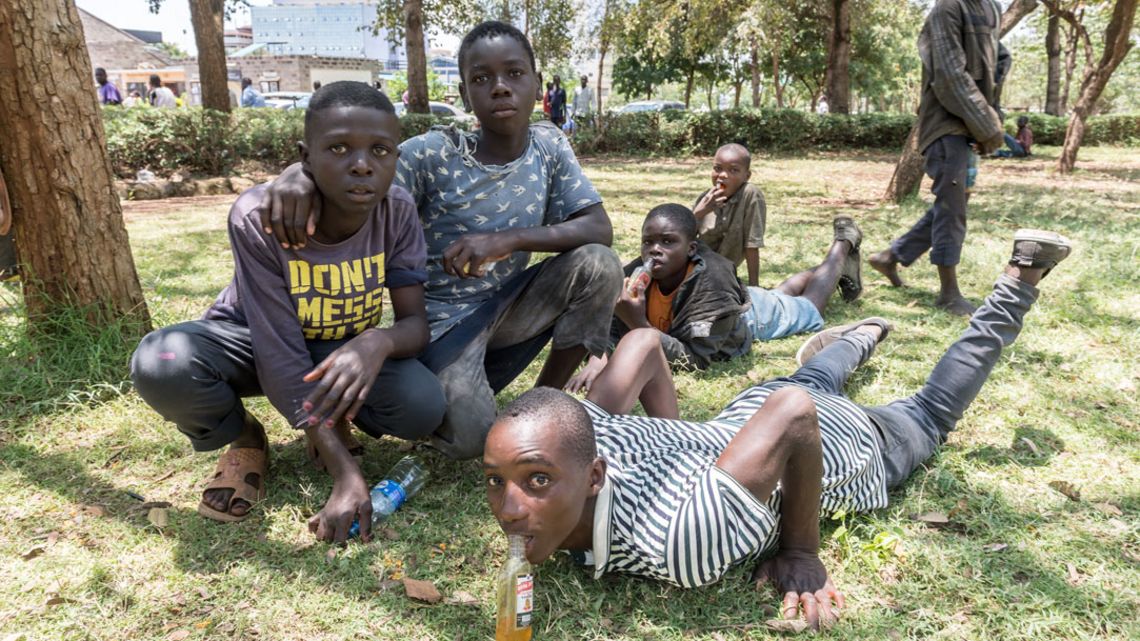 Gruppe von fünf Jungen in einem Park, ein Junge liegt auf dem Boden 