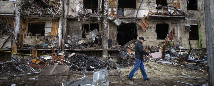 Ein Mann geht an einem durch russische Raketen zerstörten Gebäude in Kiew vorbei.