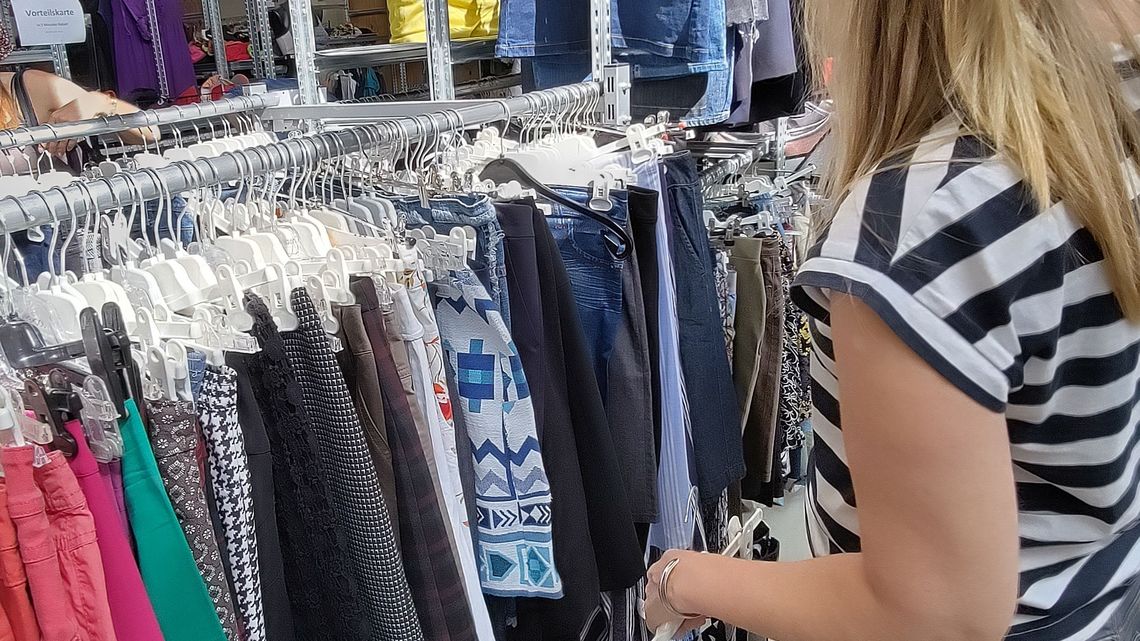 Eine Frau sucht sich Kleidungsstücke von einem Kleiderständer aus