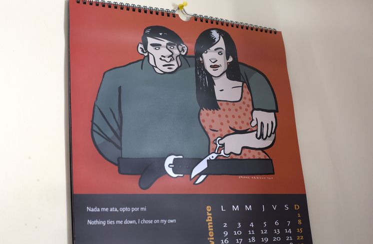Ein Kalender hängt an der Wand. Das Kalenderbild zeigt eine Frau die den Gürtel des Mannes durchschneidet.