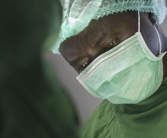 Arzt während einer Operation, trägt OP-Kleidung und Mundschutz
