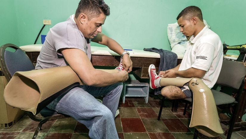 Gemeinsam bereiten Miguel Elcides (Person rechts, 21 Jahre) und der Prothesenhersteller Walter Geovanis Aguilar Turcios (33 Jahre) die nachjustierten und angepassten Oberschenkelprothesen fuer die erste Gehprobe auf der Laufstrecke vor.