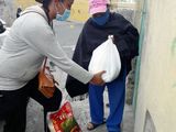 Übergabe eines Lebensmittelpaketes durch eine Mitarbeiterin von INREDH