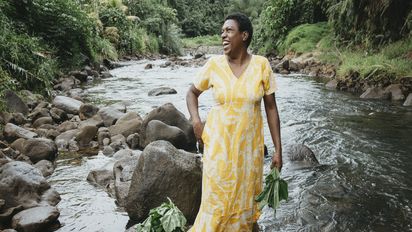 Luisa Curuki aus Fidschi steht am Fluss hinter ihrem Haus.