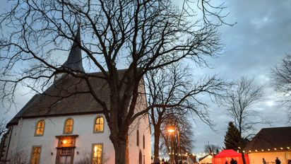 Weihnachtsmarkt an einer Kirsch bei Dämmerung mit Lichterketten beleuchtet