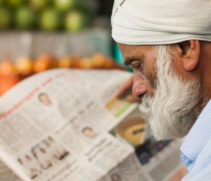 Ein Mann liest auf einem Markt in Munnar eine Zeitung