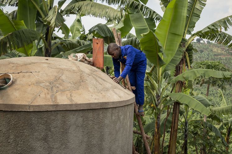 Maurer Pedson Biryomunsi zeigt, wie man einen von ACORD gebauten Wassertank auf dem Grundstück eines Hauses im Distrikt Rwampara baut und reinigt. Projektpartner: ACORD - Agency for Cooperation in Research and Development