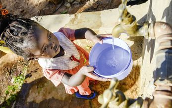 KENIA, ADS Anglican Development Services of Mount Kenya East, Stadt Embu, Dorf Gichunguri, Projekt Regenwasserauffang an einem Felsen und Speicherung in Tanks zur Nutzung in Duerreperioden, Agnes Irima, 44 Jahre, und Enkelin an Wasserstelle