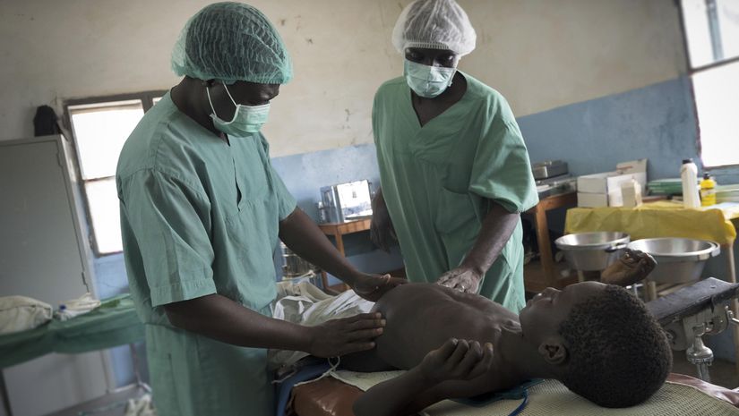 Chirurg und OP-Assistent tasten angeschwollenen Bauch eines Jungen ab