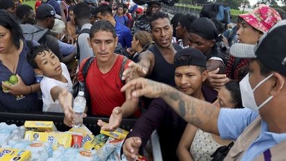 Members of the Fray Matias de Cordova Human Rights Center hand out water and cereal bars to migrants and asylum seekers from Central America and the Caribbean walking in a caravan headed to the Mexican capital to apply for asylum and refugee status, on a highway in Mapastepec, in Chiapas state, Mexico August 31, 2021. REUTERS/Jose Torres REFILE - CORRECTING HUMAN RIGHTS CENTER'S NAME