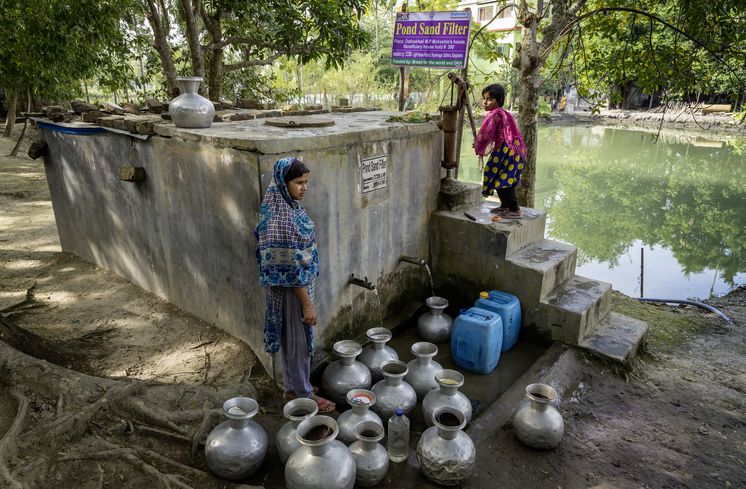 CCDB Bangladesch Frauen und Maedchen aus der Umgebung vom CCDB Brunnen in der naehe von Shyamnagar, wo das Wasser mit Sandfilterung aufbereitet wird, fuellen ihre Wasserkruege und haben oft weite Wege zu ihren Haeusern zurueckzulegen. Die Menschen in den kleinen Siedlungen an den Fluessen in der Naehe von Shyamnagar in Sued Bangladesch, spuehren deutlich den Klimawandel. Der Meeresspiegel steigt und Daemme werden zerstört. Da durch werden Felder und die wichtigen Suesswasserteiche ueberflutet und versalzen. CCDB Bangladesch arbeitet an Suesswassergewinnungs-Projekten und sorgt dafuer, dass die Menschen nach und nach sauberes Trinkwasser erhalten.