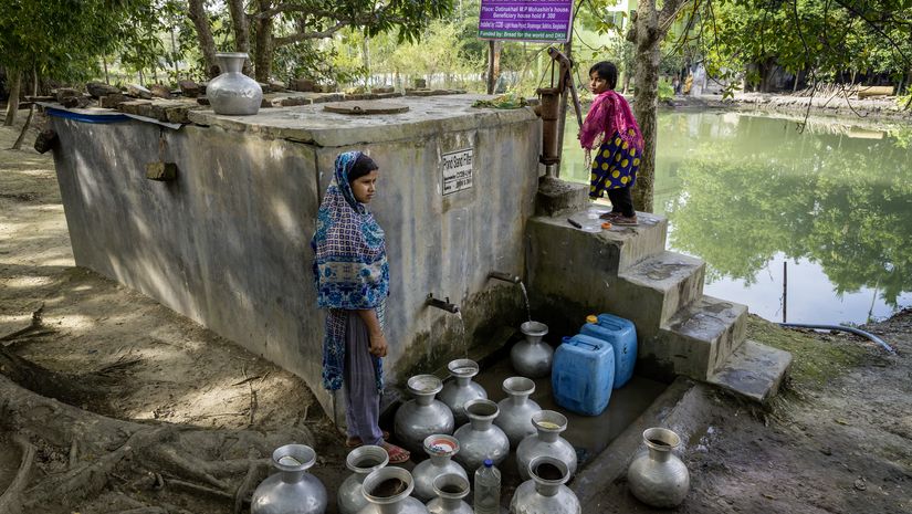 zwei Mädchen füllen Wasserkrüge an dem CCDB Brunnen in dem das Wasser durch eine Sandfilterung aufbereitet wird