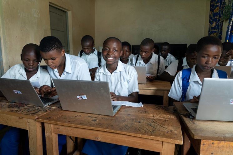 Zusammen mit ihren Mitschüler*innen übt die Schülerin Bien Aimé Ambire Namegabe (Vordere Reihe, 3. Person v. links, 14 Jahre) in der Informatik-Klasse mit der Betreuung des Informatik-Lehrers Kasholya Konkwa ihre ersten Schritte am Laptop. In der Informatik-Klasse teilen sich je zwei Schüler*innen ein Laptop. Im November 22 hat das „Institut Namurhera“ sechs Laptops von der Organisation RIO bekommen. Projektpartner: RIO-Réseau d'Innovation Organisationnelle.