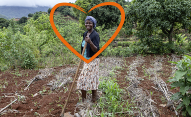 Eine Kleinbäuerin steht zufrieden auf ihrem Feld, eingerahmt in ein Herz.