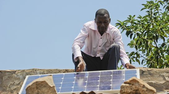 Landwirt in Angola mit Solarpanel auf seinem Hausdach