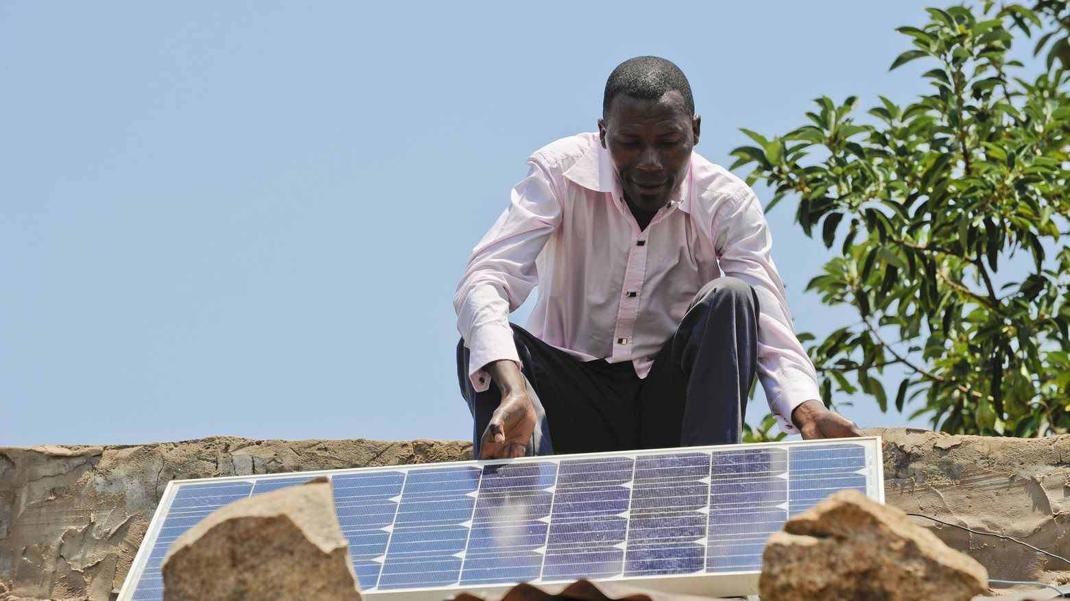 Landwirt in Angola mit Solarpanel auf seinem Hausdach