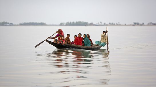 Klimawandel in Bangladesch Überschwemmungen in Bangladesch. Menschen sitzen in einem Boot.