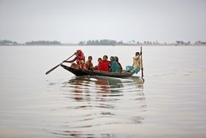 Überschwemmungen in Bangladesch. Menschen sitzen in einem Boot.