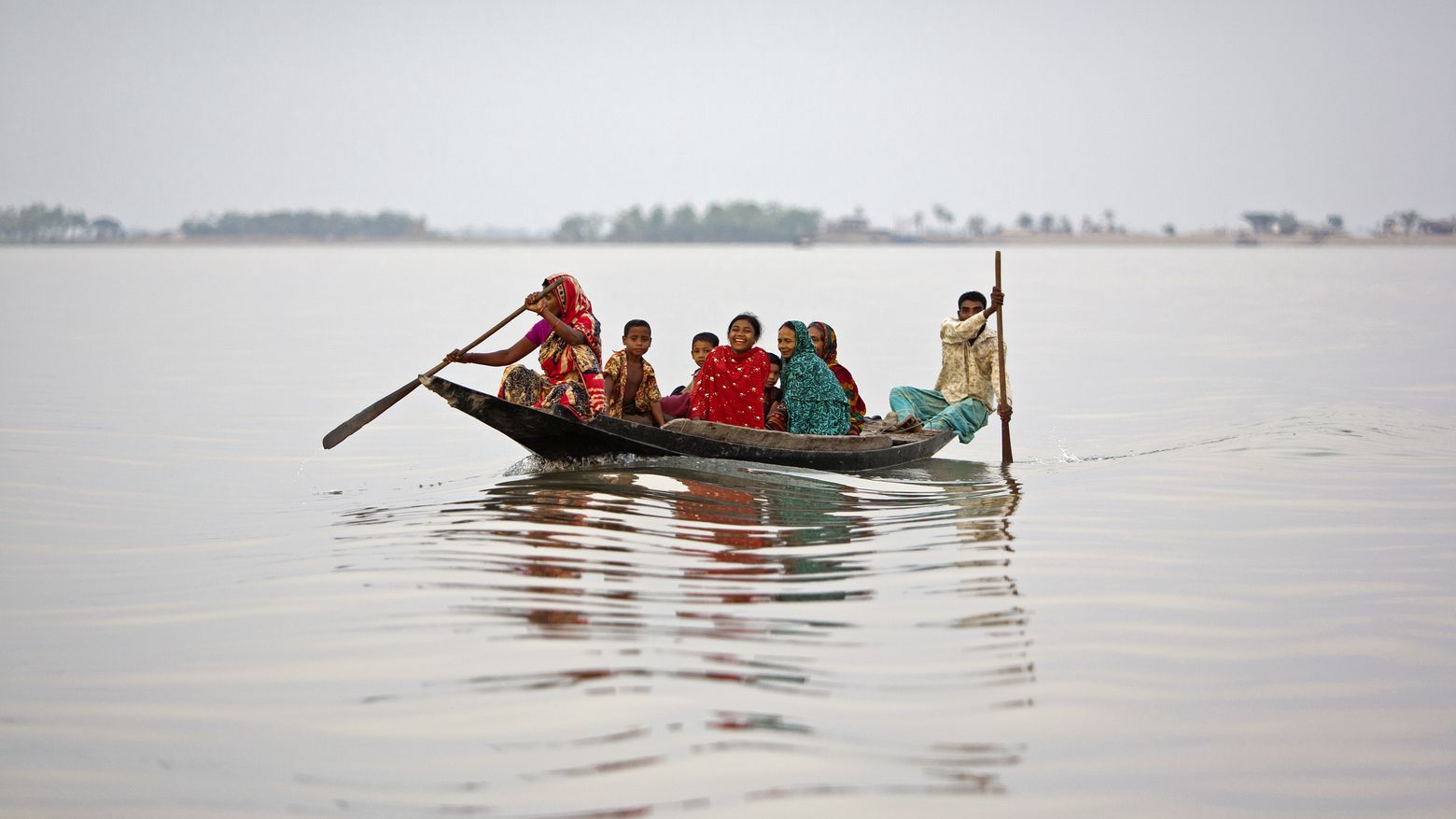 Überschwemmungen in Bangladesch. Menschen sitzen in einem Boot.