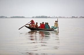 Überschwemmungen in Bangladesch. Menschen sitzen in einem Boot.