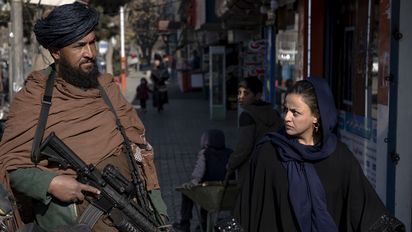 FILE - A Taliban fighter stands guard as a woman walks past in Kabul, Afghanistan, on Dec. 26, 2022. The United Nations' human rights chief on Tuesday Dec. 27, 2022 decried increasing restrictions on women's rights in Afghanistan, urging the country's Taliban rulers to reverse them immediately. He pointed to “terrible consequences” of a decision to bar women from working for non-governmental organizations. (AP Photo/Ebrahim Noroozi, File)