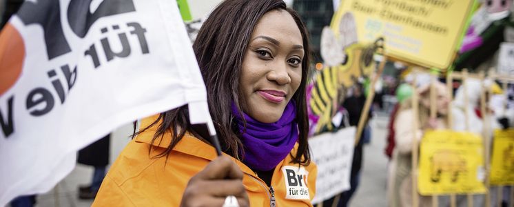 Frau mit einer Brot für die Welt Jacke und Fahne auf einer Demonstration