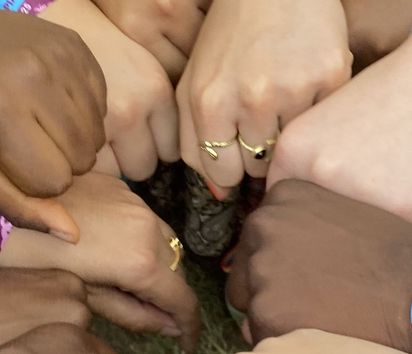 mehrere Hände treffen sich in der Mitte eines Kreises aus Armen