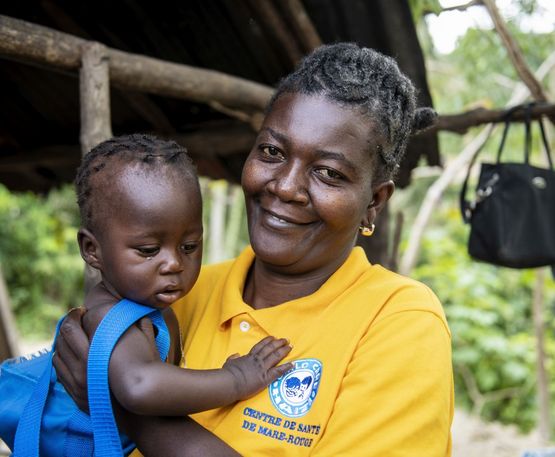 Hebamme Ismanie Joseph mit einem Kleinkind im Arm