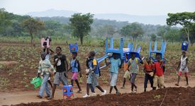 In Kwanza Sul, Angola, Afrika tragen Kinder Plastikstühle bei einem ländlichen Entwicklungsprojekt.