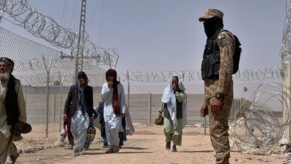 FILE - In this Aug. 20, 2021, file photo, Pakistani army soldier stands guard while Afghan people enter into Pakistan through a border crossing point, in Chaman, Pakistan. Chaman is a key border crossing between Pakistan and Afghanistan, where normally thousands of Afghans and Pakistanis cross daily and a steady stream of trucks passes through, taking goods to Afghanistan. (AP Photo/File)