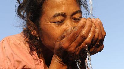 Dorfbewohnerin an ihrem Wasserhahn bzw. Wasserstelle