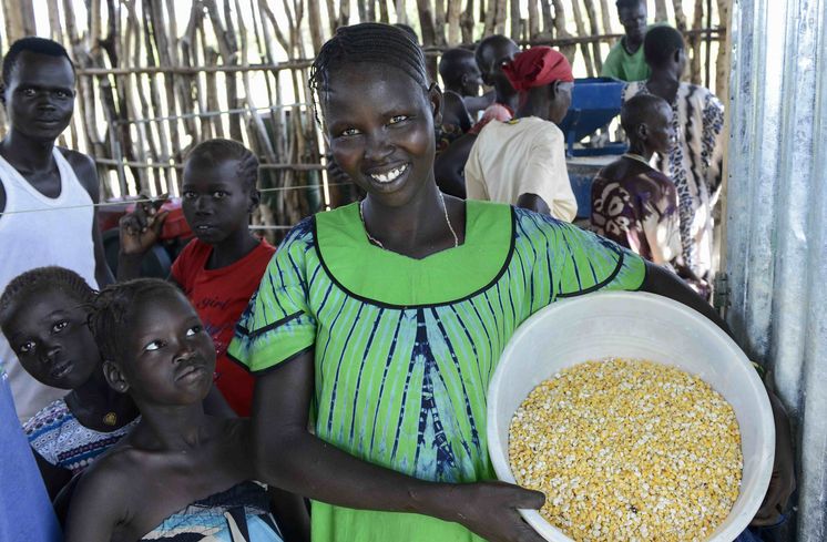 Neues Leben für Kriegsflüchtlinge aus Südsudan AETHIOPIEN, Gambela, Projekte EECMY-DASSC, Region Itang, Dorf Pilual der Ethnie NUER,Herr Mun Kunen und Frau Neelam , sie sind vor dem Buergerkrieg aus dem Suedsudan gefluechtet, seine Frau Neelam, gruenes Kleid, in der Getreidemuehle des Projektes - Projektpartner Ethiopian Evangelical Church Mekane Yesus/Development and Social Service Commission (EECMY-DASSC)